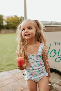 PINK DESERT GIRLS MINI RUFFLE LEG SCOOP ONE PIECE SWIMSUIT IN POPSICLE