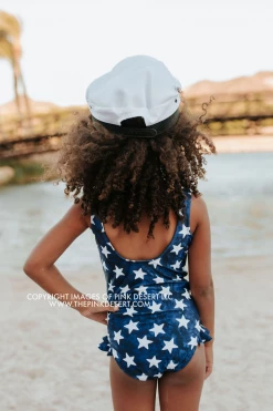 PINK DESERT GIRLS MINI RUFFLE LEG SCOOP ONE PIECE SWIMSUIT IN SPANGLED STAR PRINT