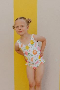 GIRLS MINI RUFFLE LEG SCOOP ONE PIECE SWIMSUIT IN CITRUS PRINT BY SASSY RED LIPSTICK X PINK DESERT
